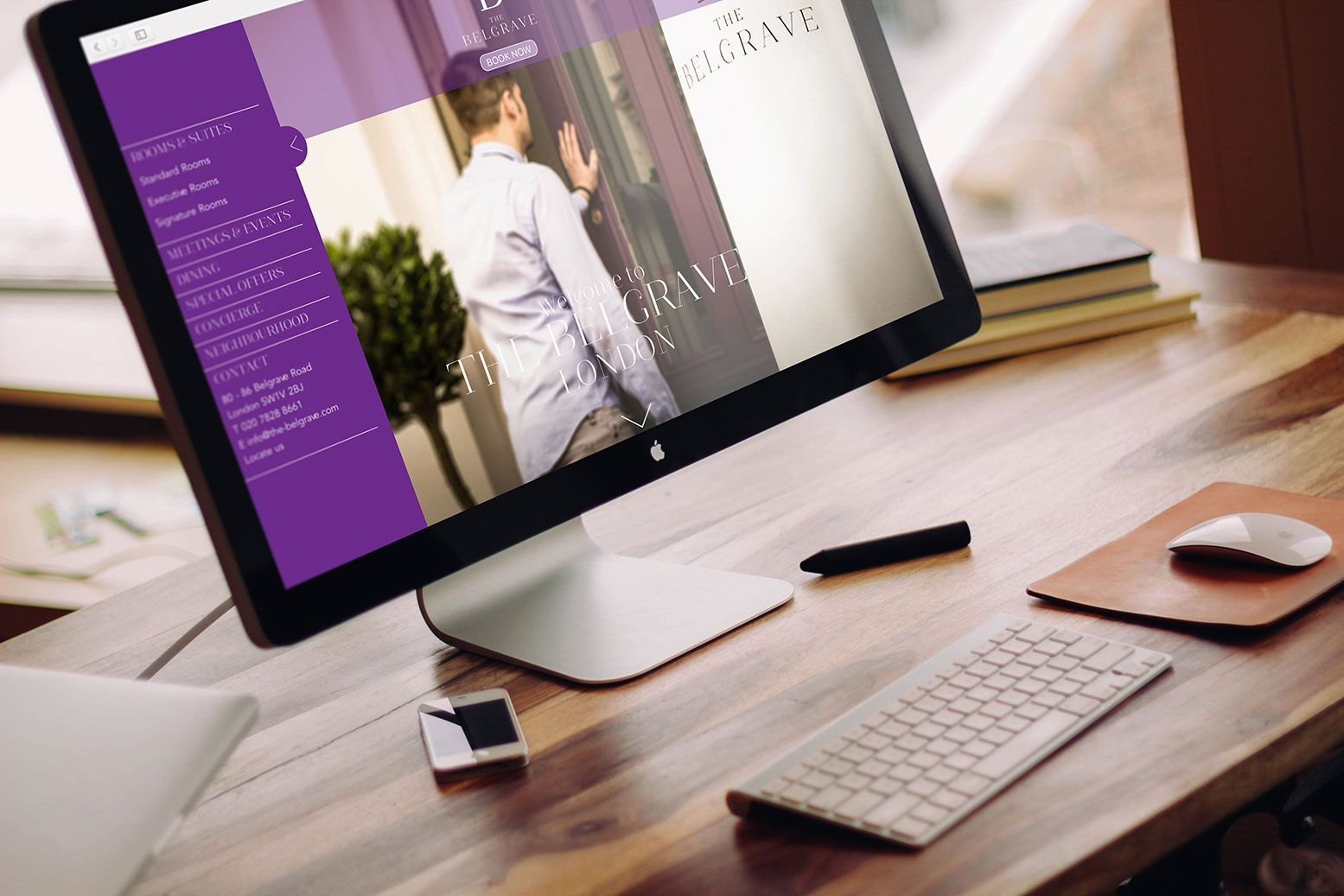 A mac on a desk and surround desk elements featuring the home page of the Belgrave hotel website
